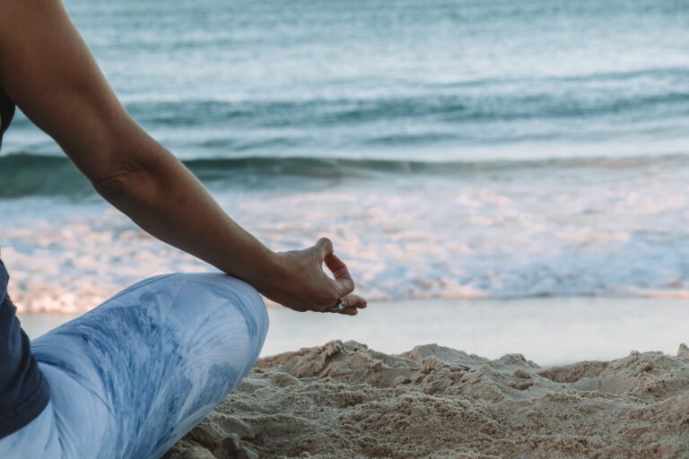 Woman meditating on beach. How properly managed stress becomes beneficial. Mindletic Blog