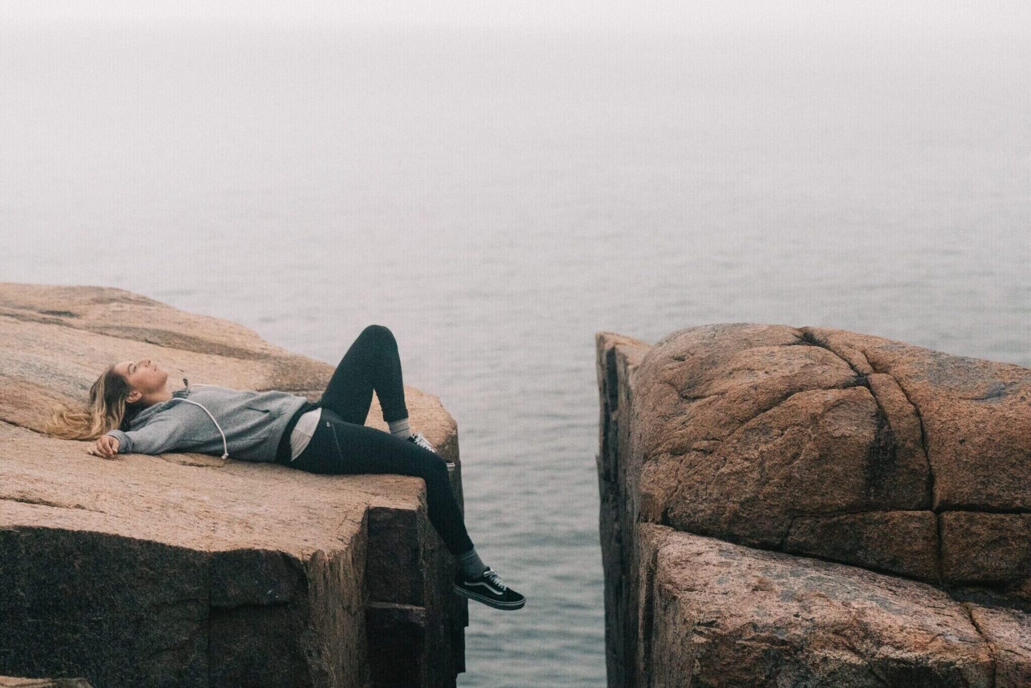 Exhausted young woman lying on the rock. What is fatigue? Mindletic Blog