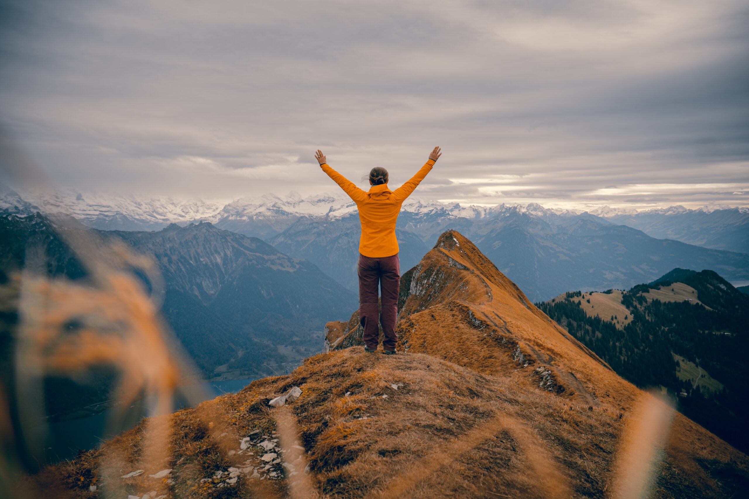 Woman raised her hands up after climbing to the top of the mountain. The discovery of motivation. Mindletic Blog.