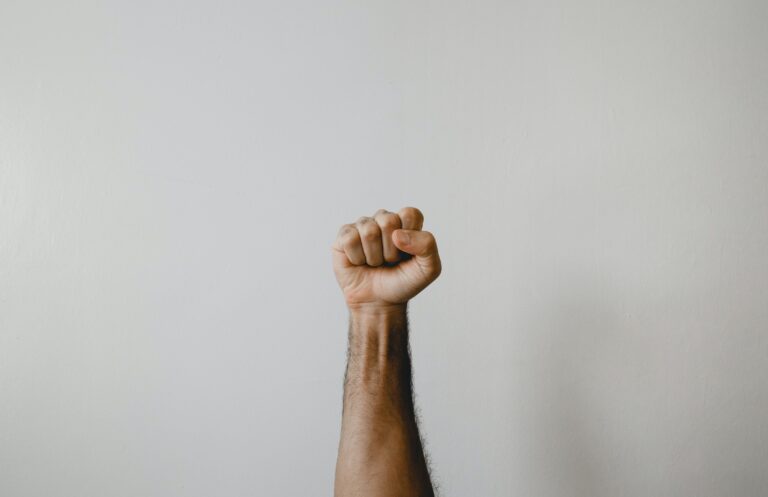 Fist raised in white background. The power of psychological resilience. Mindletic blog