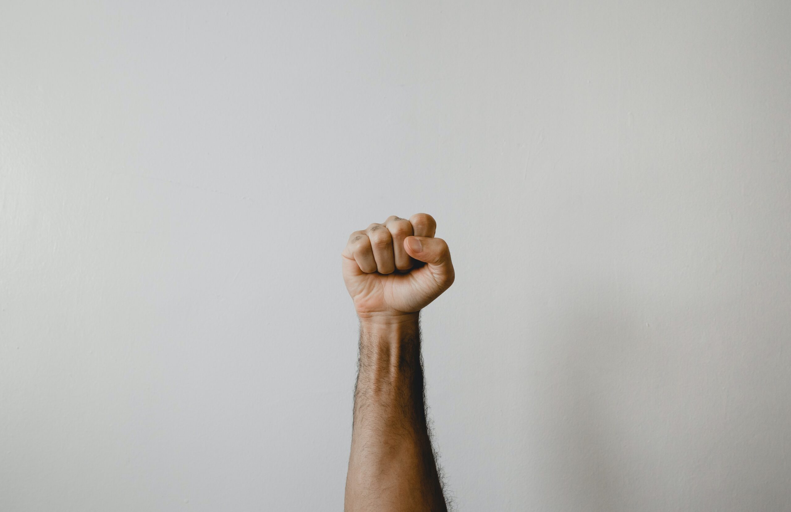 Fist raised in white background. The power of psychological resilience. Mindletic blog